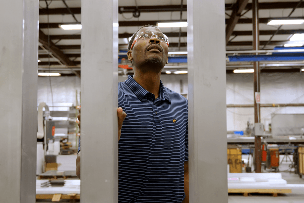 Engineer sighting down an aluminum extrusion to check straightness on the Apopka floor