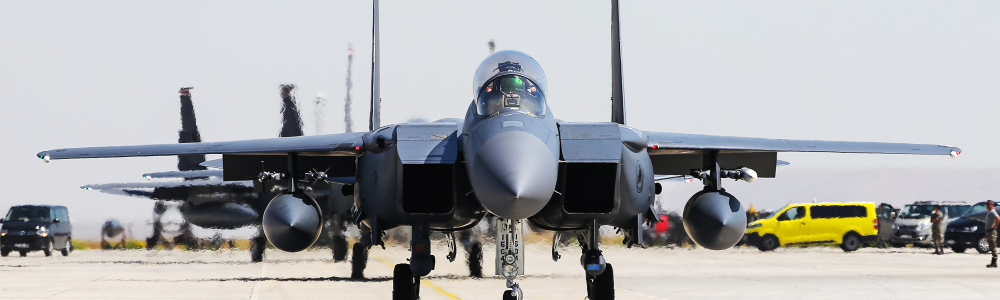 F-15 aircraft on the flight line with ground crews and support vehicles